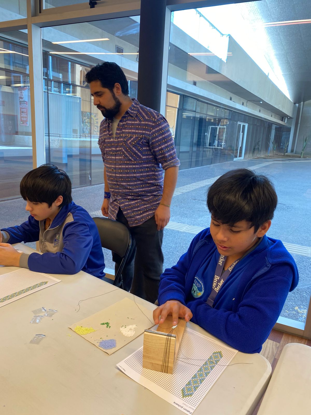 Artista y experto, Mateo Perea, verificando los tejidos de sus jóvenes aprendices.